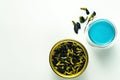 A cup of hot blue tea with milk and dried flowers on a white table. Royalty Free Stock Photo