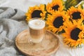 Cup with hot cappuccino, gray pastel woolen blanket, sunflowers, bedroom Royalty Free Stock Photo