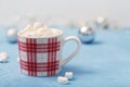 A cup of hot chocolate with marshmallows on a blue background with silver Christmas decorations on the table Royalty Free Stock Photo