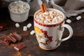 Cup of hot chocolate with marshmallows and cinnamon stick on old wooden table. Royalty Free Stock Photo