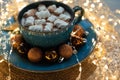 Cup of hot chocolate with marshmallows decorated Christmas baubles and defocused lights on gray wooden background. Christmas and Royalty Free Stock Photo