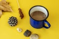 A cup of hot cocoa with fallen leaves, small dry pinecone and stones on plain yellow background Royalty Free Stock Photo