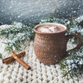 Cup of hot cocoa or hot chocolate on knitted background with fir tree and snow effect, traditional beverage for winter time Royalty Free Stock Photo