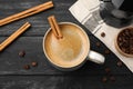 Cup of hot coffee with aromatic cinnamon on black wooden table, flat lay Royalty Free Stock Photo