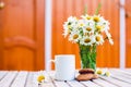 Cup of hot coffee, biscuits and a bouquet of chamomiles. Royalty Free Stock Photo