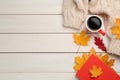 Cup of hot coffee, book, sweater and autumn leaves on white wooden table, flat lay. Space for text