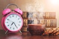 A cup of hot coffee and cookies near books and a clock in a library or study Royalty Free Stock Photo