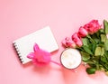 The cup of hot coffee, empty notepad with funny pen and bouquet of fresh roses on soft pink background Royalty Free Stock Photo