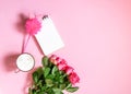 The cup of hot coffee, empty notepad with funny pen and bouquet of fresh roses on soft pink background Royalty Free Stock Photo