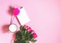 The cup of hot coffee, empty notepad with funny pen and bouquet of fresh roses on soft pink background Royalty Free Stock Photo