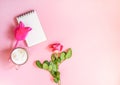 The cup of hot coffee, empty notepad with funny pen and bouquet of fresh roses on soft pink background Royalty Free Stock Photo