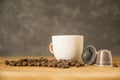 Cup of hot coffee and ground coffee in capsules from coffee beans on a wooden table of a rustic kitchen. Smoke, aroma Royalty Free Stock Photo