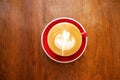 Cup of hot coffee with latte art in leaf shape on wooden table. Top view. Royalty Free Stock Photo