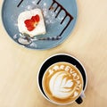 A cup of hot coffee latte and a slice of strawberry cake with cream Royalty Free Stock Photo