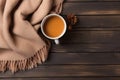 Cup of hot coffee with milk on brown wooden background. Warm beige scarf creates a cozy atmosphere. Royalty Free Stock Photo