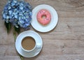A cup of hot coffee with Pink-colored sweet donuts with blue Hydrangea flower