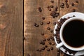 A cup of coffee and roasted coffee beans around on a brown wooden table with a place for inscription Royalty Free Stock Photo