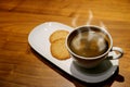 Cup of Hot Coffee with Smoke Served with Butter Cookies on the Wooden Table Royalty Free Stock Photo