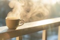 cup of hot coffee with steam on a balcony railing