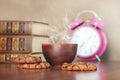Cup of hot coffee or tea and cookies near books and alarm clock Royalty Free Stock Photo