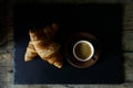 Cup of hot coffee with two fresh croissants against dark background Royalty Free Stock Photo