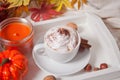 Cup of hot creamy cocoa with froth on the white tray with autumn leaves and pumpkins on the background Royalty Free Stock Photo