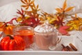 Cup of hot creamy cocoa with froth on the white tray with autumn leaves and pumpkins on the background Royalty Free Stock Photo