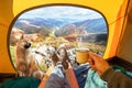 Cup of hot drink in the hand and wonderful view of autumn mountain tops through the open entrance of the tent. The beauty of a Royalty Free Stock Photo