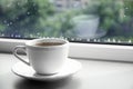 of hot drink on window sill against glass with rain drops, space for text Royalty Free Stock Photo