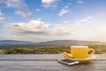 A cup of hot espresso coffee mugs placed with smartphone on a wooden floor with morning fog and moutains with sunlight background, Royalty Free Stock Photo