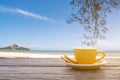 A cup of hot espresso coffee mugs placed on a wooden floor on sea view with sunlight background,coffee morning