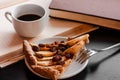 Cup of hot fragrant black morning coffee and piece of apple pie stands on a open book. Light brown warm colors.