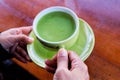 Cup of hot milk green tea in hand above the table Royalty Free Stock Photo
