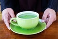 A cup of hot milk green tea in hands on the table Royalty Free Stock Photo