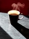 Cup of hot morning coffee on a black table on a sunny day