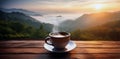 A cup of hot morning coffee with steam on a wooden table against a beautiful background of sunrise scene in the mountains. Royalty Free Stock Photo