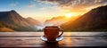 A cup of hot morning coffee with steam on a wooden table against a beautiful background of sunrise scene in the mountains. Royalty Free Stock Photo