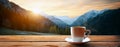 A cup of hot morning coffee or tea on a wooden table against a beautiful background of sunrise scene in the mountains. Royalty Free Stock Photo