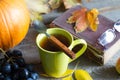 Cup of hot tea autumn leaves book and glasses cold day abstract still life on wooden boards