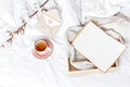 Cup of hot tea branch of cotton wooden tray knitted plaid sweater open notebook love letter in bed. Cozy morning breakfast at home