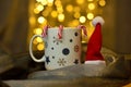 A cup of hot tea in Christmas version with hat of santa claus and candy canes