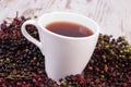 Cup of hot tea with elderberry juice and heap of berry