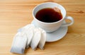 Cup of hot tea with heap of teabags isolated on wooden table