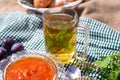 Cup of hot tea with mint in a transparent glass, next to a vase with berry jam in the fresh air. Seasonal still life Royalty Free Stock Photo