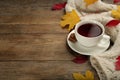 Cup of hot tea, sweater and autumn leaves on wooden table, space for text Royalty Free Stock Photo