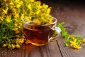 Cup with Hypericum perforatum St Johns wort or tutsan plant drink with fresh flowers