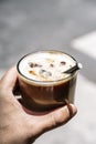 Cup of iced latte cappuccino coffee in hand on city street. Takeaway coffee drink Royalty Free Stock Photo