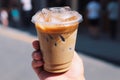 Cup of iced latte cappuccino coffee in hand on city street. Takeaway coffee drink Generative AI. Royalty Free Stock Photo