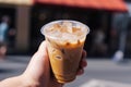 Cup of iced latte cappuccino coffee in hand on city street. Takeaway coffee drink Generative AI. Royalty Free Stock Photo