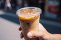 Cup of iced latte cappuccino coffee in hand on city street. Takeaway coffee drink Generative AI. Royalty Free Stock Photo